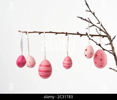 decorative plastic pink easter egg hanging on a branch, decor on a white background Stock Photo
