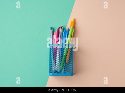 blue metal container for stationery, inside multi-colored plastic pens, top view Stock Photo