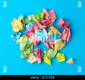 crumpled multi-colored paper stickers, top view, blue background, close up Stock Photo
