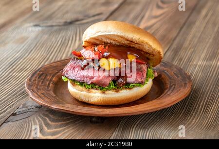 Burger with grilled steak and bell peppers on wooden board Stock Photo