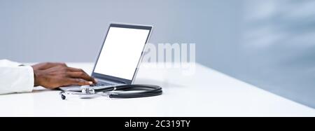Midsection Of Male Doctor Using Laptop At Desk In Clinic Stock Photo