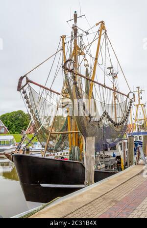 Idyllic port scenery including a shrimp cutter seen in Greetsiel, a idyllic village located in East Frisia, Northern Germany Stock Photo