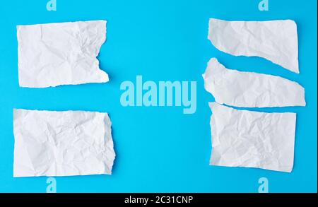 crumpled white sheet of paper torn on a blue background. Paper piece torn edge. Stock Photo