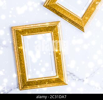 Golden photo frame and glowing glitter snow on marble flatlay background for Christmas and winter holidays Stock Photo