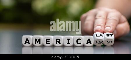 Hand turns dice and changes the expression 'America first' to 'America last'. Stock Photo