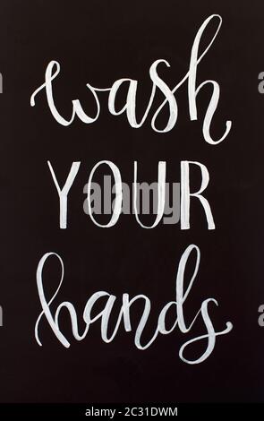 Chalk inscription WASH YOUR HANDS on a black chalkboard. Handwritten lettering Stock Photo