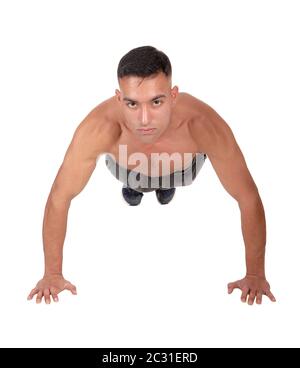 A young east Indian man doing his push aps on the floor in the studio looking into the camera, isolated for white background Stock Photo