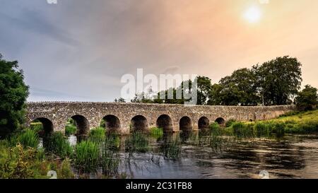 Old 12th century stone arch bridge over a river. Count Meath, Ireland Stock Photo