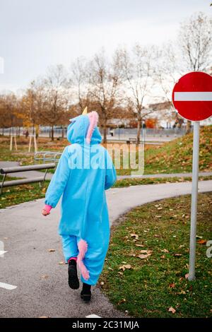 beautiful young woman wearing turquoise unicorn onesie in urban environment Stock Photo