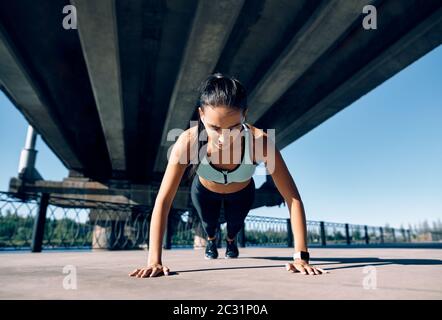 Young athletic woman doing push ups outdoors in urban city background Stock Photo