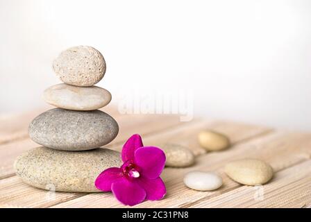 zen style still life with pink orchid flower and stone cairn Stock Photo