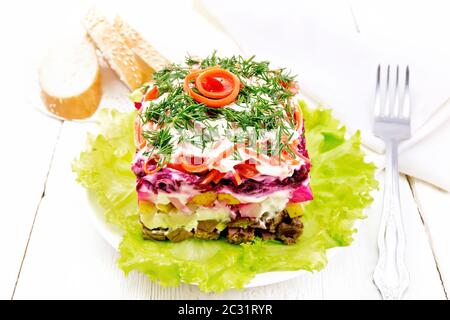 Puff salad with beef, boiled potatoes and beets, pears, spicy Korean carrots, seasoned with mayonnaise and garnished with dill on a green lettuce in a Stock Photo