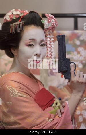 Maiko in kimono holding a plastic gun in her hand. Stock Photo