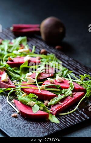 Fresh salad from beetroot, cheese and rocket salad on black wood background Stock Photo