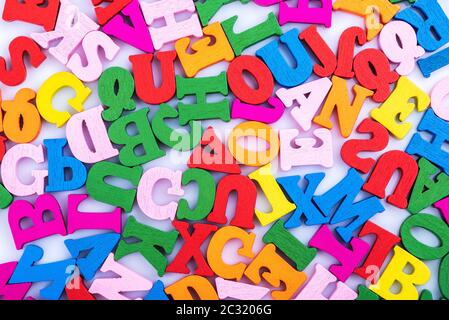 Letters of the alphabet are wooden scattered randomly macro photography isolated on a white background. Close up. Stock Photo