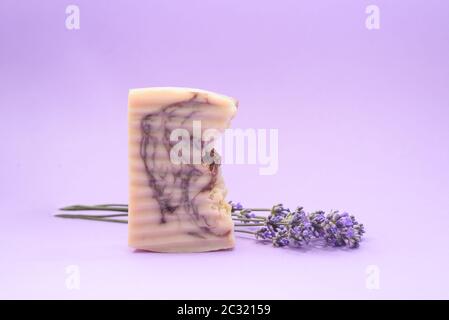A handmande organic soap with beautiful fresh lavender near it on the purple background. Organic Spa Cosmetics. Close up. Copy Space. Stock Photo