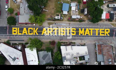 Austin, TX USA June 18, 2020: City of Austin yellow letters spelling 'Black Artists Matter' are painted in the historically black neighborhood of East 11th Street in Austin after a coalition of artists and activists finished the mural. The painting came two days after the same group painted 'Black Austin Matters' on Austin's Main Street, Congress Avenue.Credit: ATXN via Bob Daemmrich/Alamy Live News Stock Photo