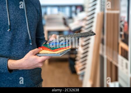 the man chooses the floor covering from the color book to the nursery in the floor shop. Stock Photo