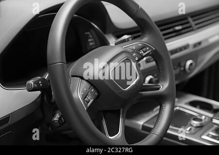 Leather multifunction steering wheel in the cabin of a premium car. Installed under the steering wheel control switches additional functions. Behind the wheel. Stock Photo