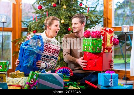 Happy man and woman sitting with presents under Christmas tree Stock Photo