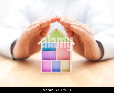 Colorful wooden house protected by hands Stock Photo
