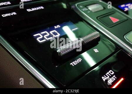 Climate control panel in the interior of the premium car. The screen temperature is set at 22 degrees. Black glossy surface. Stock Photo