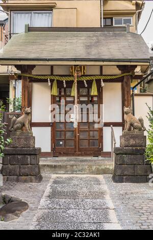 Two statues of foxes inari, deity of rice in the Shinto shrine of Mejiro Toyosaka Inari Jinja in Tokyo. Stock Photo