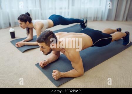 Morning fitness workout of family couple at home. Active man and woman in sportswear doing push up exercise in their house, healthy lifestyle, physica Stock Photo