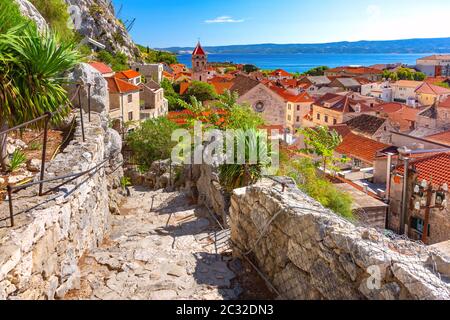 Sunny beautiful view of red roofs, Old city street with stone stairs and church in town and port Omis, very popular tourist spot in Croatia Stock Photo