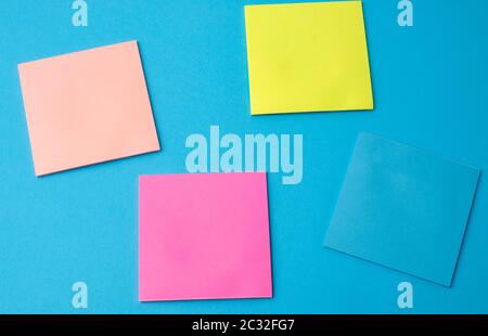 multicolored blank paper stickers of different colors on a blue background, copy space Stock Photo