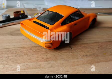 The process of assembling and painting the scale model of the car. Orange sports car in miniature. Installed taillights Stock Photo