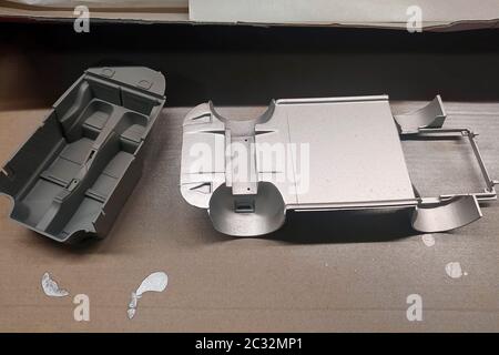 Unprimed and primed parts of a scale model car for assembly. Body and car interior. Modeling. Painting a toy car. Stock Photo