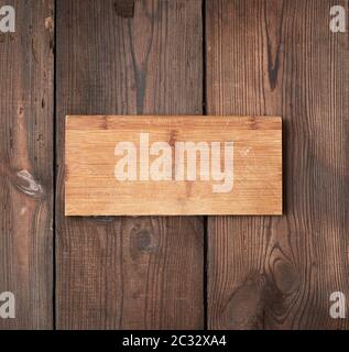 very old empty wooden rectangular cutting board, top view, brown wooden background Stock Photo