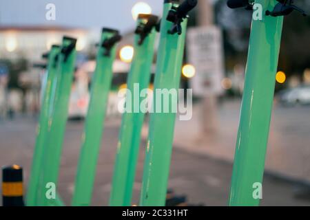 Green electric scooters for rent parked on the city. Stock Photo