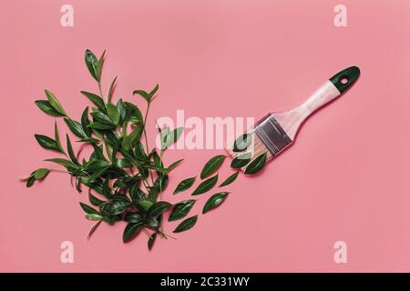 Colorful conceptual art background of paintbrush painting green leaves in shape of check mark on pink backdrop. Spring and summer concept. Flat lay st Stock Photo