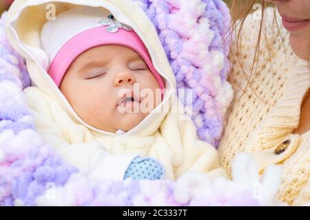 Portrait of a close-up of a two-month-old girl in her mother's arms Stock Photo