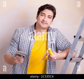 Young man applying plaster on wall at home Stock Photo