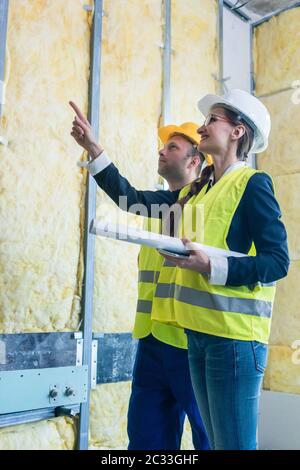 Construction manager and architect checking the insulation works in a half finished project Stock Photo