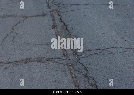 Asphalt road surface with small cracks and damages. Sidewalk asphalt road with cracks. Floor. Texture of tarmac road with cracks. Abstract background Stock Photo