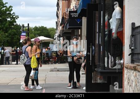 Hoboken, USA. 18th June, 2020. Practicing social distancing, women talk outside an athletic clothing store in Hoboken, NJ, June 18, 2020. After being under COVID-19 lockdown for months, new city ordinances, business such as restaurants, can expand outdoor space onto sidewalks. (Anthony Behar/Sipa USA) Credit: Sipa USA/Alamy Live News Stock Photo