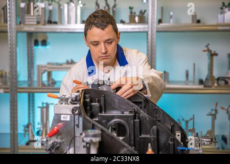 engineer measures plastic components for the production of lights for the automotive industry in a factory on a digital 3D machine. Stock Photo