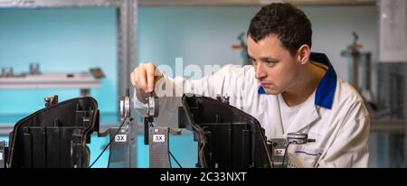 engineer measures plastic components for the production of lights for the automotive industry in a factory on a digital 3D machine. Stock Photo
