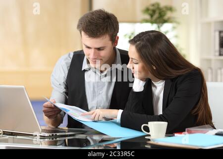 Two concentrated coworkers checking paper informs together at office Stock Photo