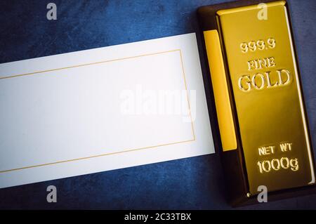 An ingot of gold metal bullion of pure brilliant diagonally located on a blue textured background Stock Photo
