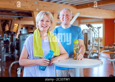 Two seniors having a break from exercising in the gym looking into camera Stock Photo