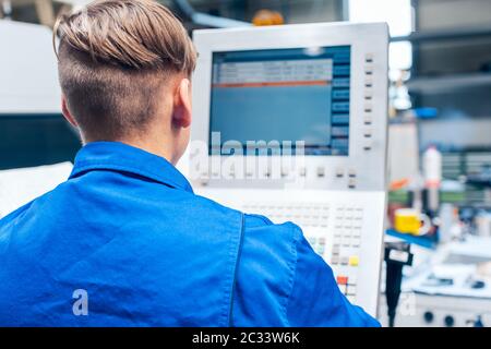 Young male worker programming lathe machine in factory Stock Photo