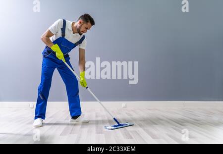 Worker Mopping Floor With Mop In Office Stock Photo