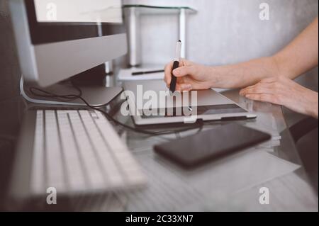 Workplace of photographer or graphic designer. Creative designer hands working on laptop with graphic tablet.  Stock Photo
