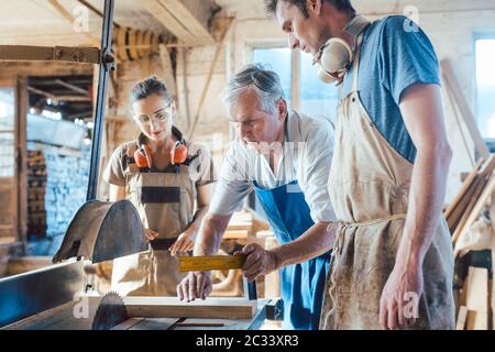 Experienced master carpenter transferring knowledge to his younger colleagues Stock Photo