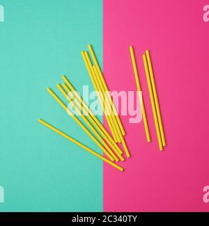 stack of yellow paper tubes for a cocktail on a multi-colored background, concept of rejection of plastic and the use of recyclable materials Stock Photo